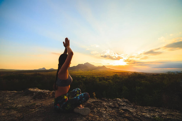 Mladá žena cvičí jógu nebo pilates při západu slunce nebo východ slunce v krásné horské lokalitě. - Fotografie, Obrázek