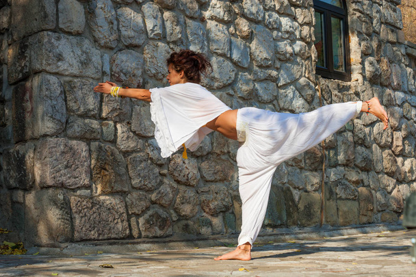 Молодая женщина практиковать йогу на открытом воздухе осенний день делает воин позировать полное тело выстрел в передней старый каменный дом
 - Фото, изображение