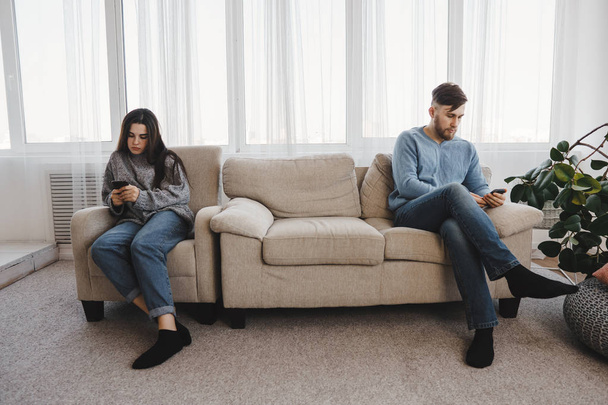 Bored couple chatting online using smart phones. - Фото, изображение
