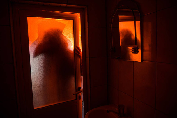 Φρίκη σιλουέτα της γυναίκας στο παράθυρο. Scary Απόκριες έννοια θολωμένη σιλουέτα της μάγισσας στο μπάνιο - Φωτογραφία, εικόνα