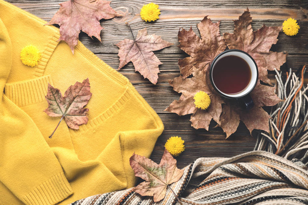 Őszi divat szezonális fogalmát, sárga meleg puha kényelmes pulóver cardigan skandináv kötött sál csésze forró fekete tea kávé alá bukott juhar levelei fából készült asztal lapos feküdt vintage felülnézet - Fotó, kép
