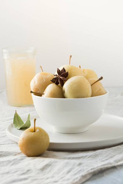 Pickled apples in bowl and apple sidr in glass on white stone table. Traditional Russian food. - Zdjęcie, obraz