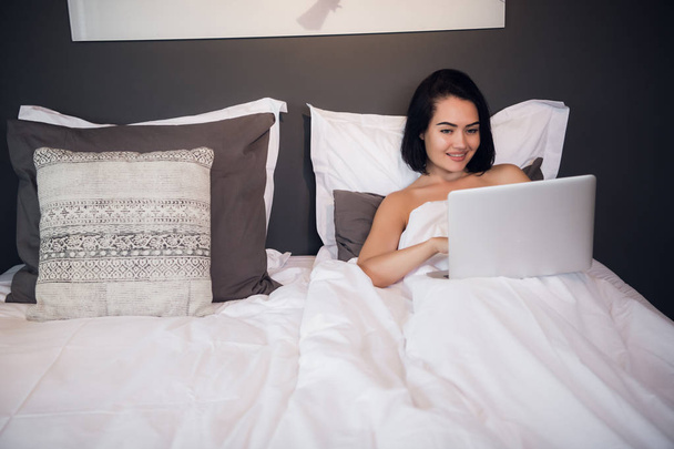 Retrato de bela jovem com laptop na cama
 - Foto, Imagem