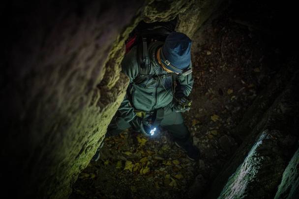 Καυκάσιος σπηλιές Explorer με πυξίδα τη συσκευή ψάχνει για σωστός τρόπος εκτός. - Φωτογραφία, εικόνα