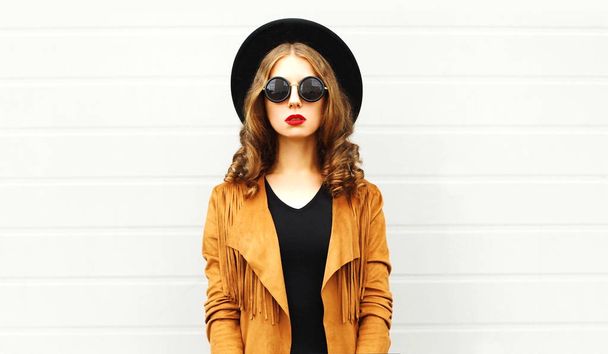Fashion woman in black round hat, sunglasses, jacket on gray wall background - Photo, image