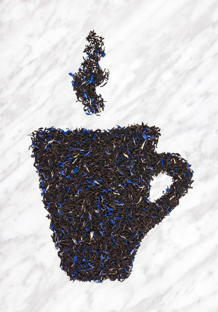 Kopje thee met stoom gemaakt van zwarte Earl gray thee bladeren, op marmeren achtergrond. - Foto, afbeelding