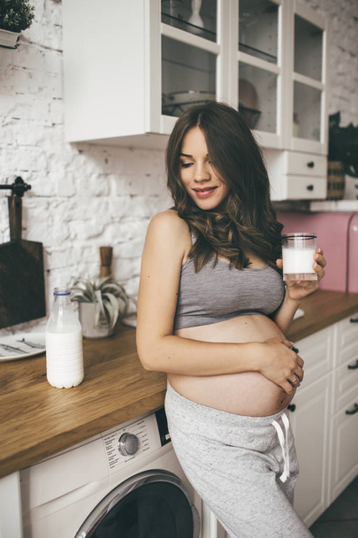 Pretty pregnant woman in kitchen with cup of milk - Valokuva, kuva