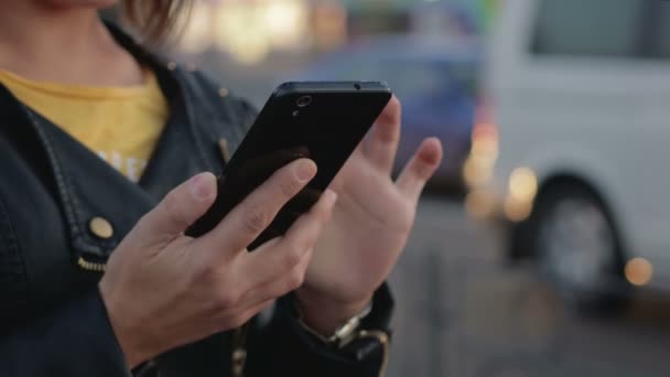 Retrato de una joven que está en la ciudad, en sus manos un teléfono inteligente, teléfono móvil
 - Metraje, vídeo