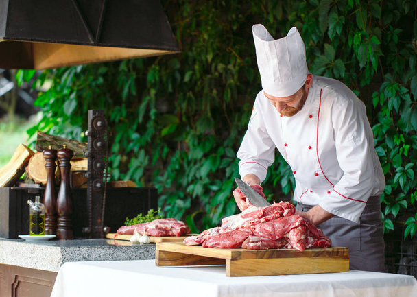 A man cook cuts meat with a knife in a restaurant. - 写真・画像