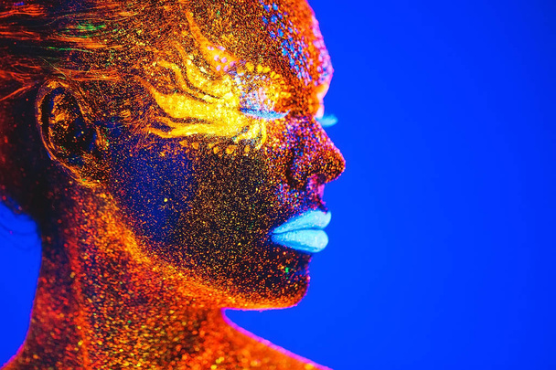 Portrait of a girl painted in fluorescent powder. - Foto, afbeelding