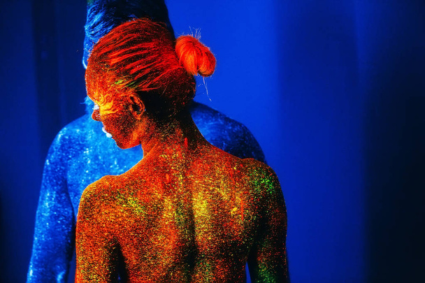 Concept. Portrait of a bearded man and woman painted in ultraviolet powder. - Φωτογραφία, εικόνα