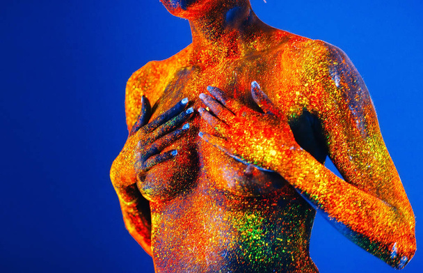Portrait of a girl painted in fluorescent powder. - 写真・画像