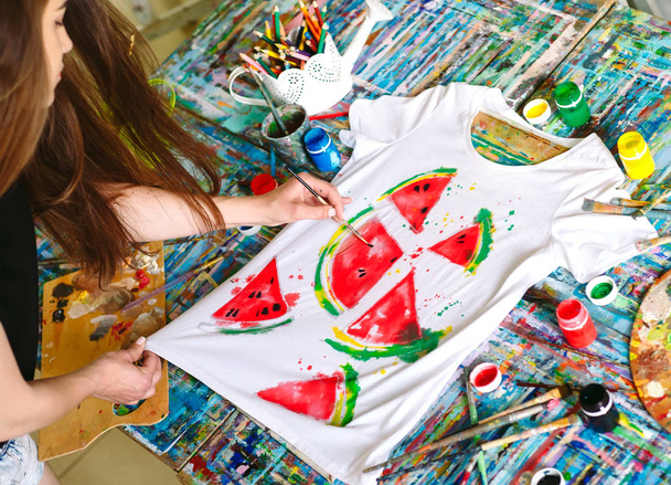 Drawing on clothes. Girl draws on a white T-shirt. - Foto, Imagen