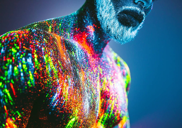 Concept. Portrait of a bearded man. The man is painted in ultraviolet powder. - Foto, Imagen