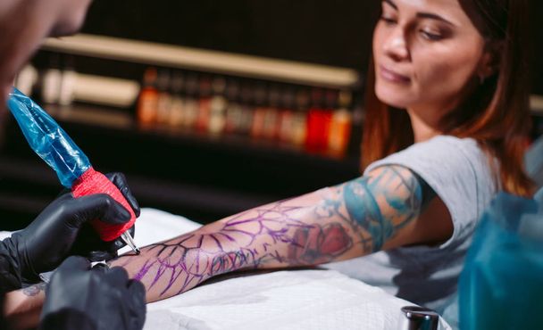 Professional tattoo artist makes a tattoo on a young girl's hand. - Photo, Image
