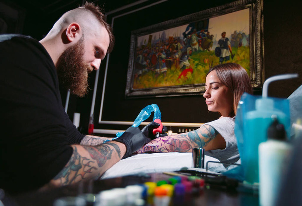 Professional tattoo artist makes a tattoo on a young girl's hand. - Fotó, kép