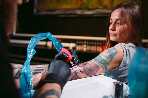Professional tattoo artist makes a tattoo on a young girl's hand. - Fotoğraf, Görsel