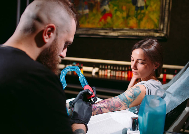 Professional tattoo artist makes a tattoo on a young girl's hand. - Φωτογραφία, εικόνα