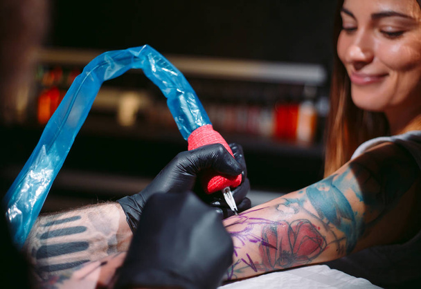 Professional tattoo artist makes a tattoo on a young girl's hand. - Photo, Image