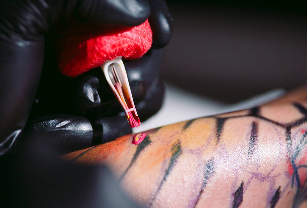 Professional tattoo artist makes a tattoo on a young girl's hand. - Foto, Bild