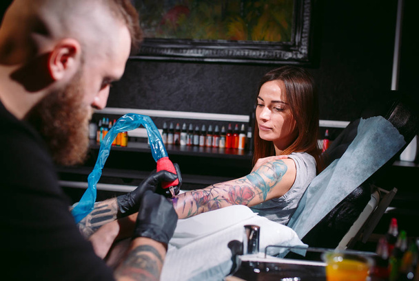 Professional tattoo artist makes a tattoo on a young girl's hand. - Photo, image