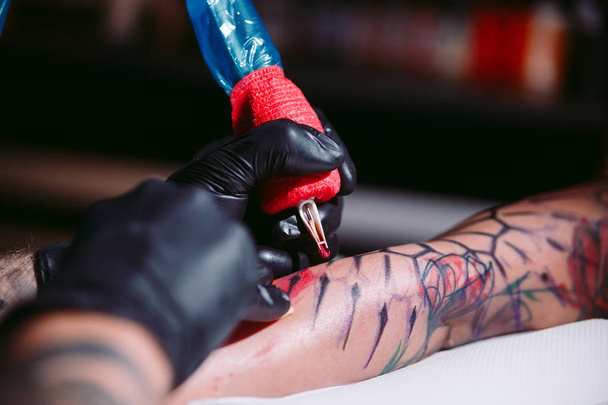 Professional tattoo artist makes a tattoo on a young girl's hand. - Fotografie, Obrázek