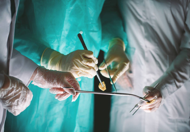 Kädet lähikuva kirurgeista, joilla on lääketieteellisiä instrumentteja. Kirurgi tekee leikkauksen.
. - Valokuva, kuva