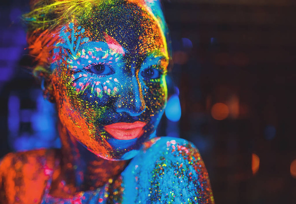 Portrait of a girl painted in fluorescent powder. - Фото, изображение