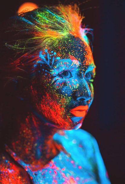 Portrait of a girl painted in fluorescent powder. - Foto, imagen