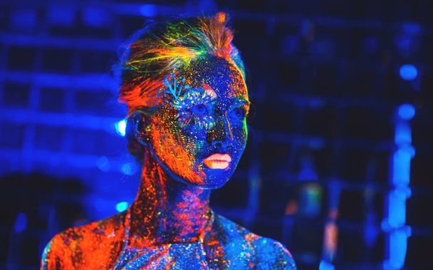Portrait of a girl painted in fluorescent powder. - Фото, изображение
