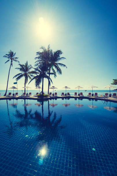 Пляж и море с зонтиком и шезлонгом вокруг бассейна на курорте для путешествий и отдыха - Фото, изображение