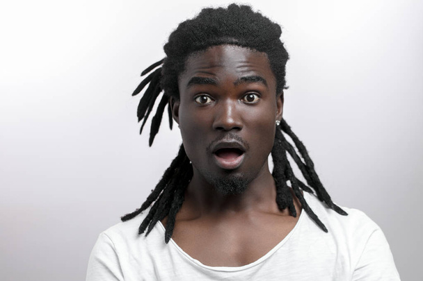 sorprendido hombre afroamericano vistiendo camiseta blanca mirando a la cámara en sorpresa - Foto, imagen
