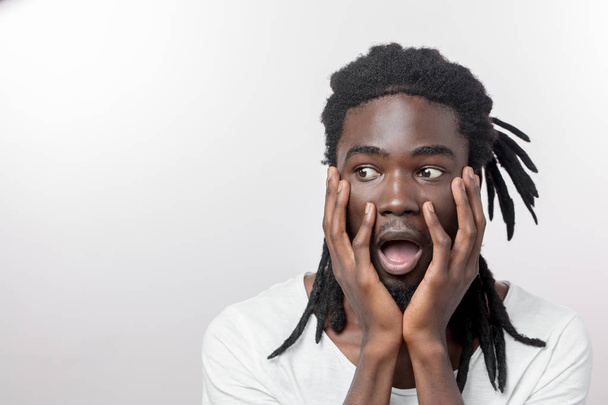 shocked African American man wearing white T-shirt looking at camera in surprise - Fotó, kép