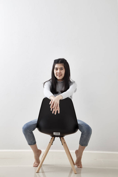 Attractive Asian girl sitting on white modern chair and relax at home. love Valentine's Day - Holiday - Фото, изображение