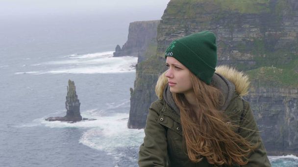Close up shot of a girl sitting at the Cliffs of Moher - Foto, imagen