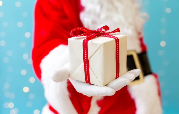 Santa holding a small Christmas gift - Photo, Image