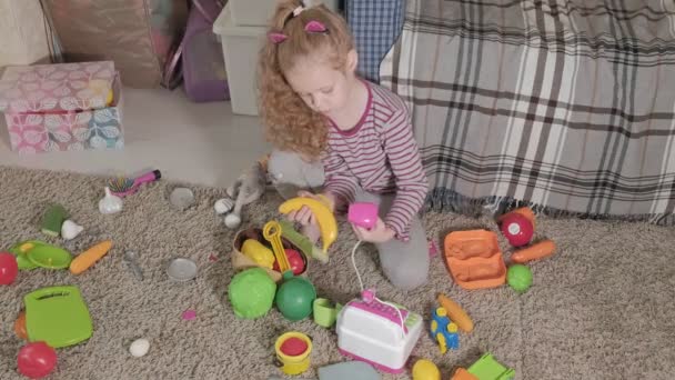 Linda criança rindo, loira pré-escolar, brincando com brinquedos coloridos, sentada no chão na sala
 - Filmagem, Vídeo