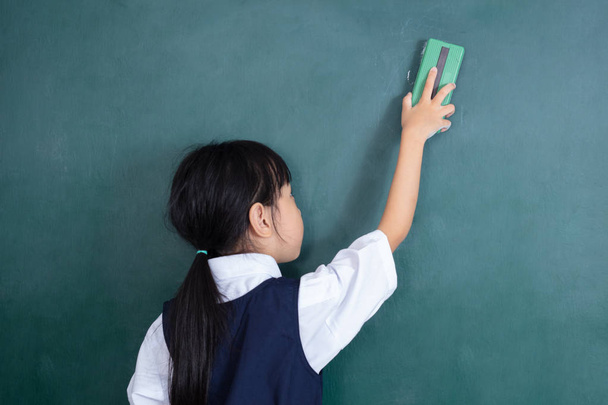 Asiática china niña limpiando la pizarra verde en el aula
 - Foto, Imagen