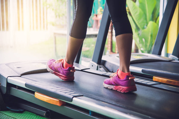 Les jambes de la fille font du jogging sur la piste dans la salle de gym
. - Photo, image
