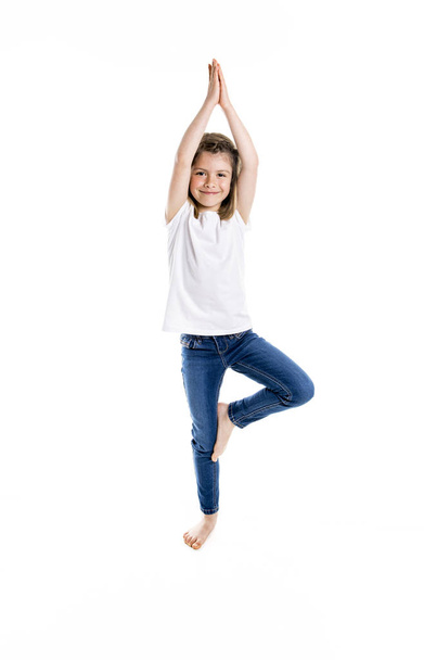 Retrato de um bonito 7 anos de idade menina Isolado sobre fundo branco fazendo ioga
 - Foto, Imagem