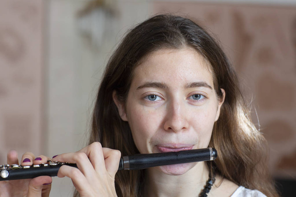A gorgeous young woman sitting and playing the flute piccolo Close-up - 写真・画像