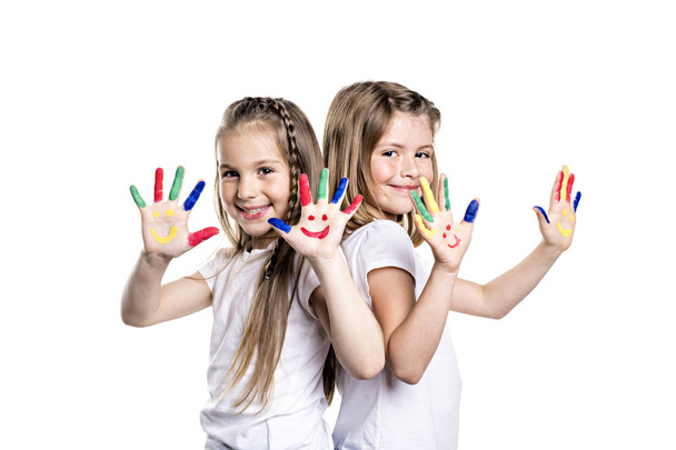 two smiling girls with the palms painted by a paint. Isolated on white background - Photo, image