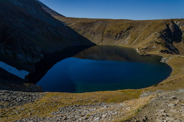 A view of Lake Okoto (The Eye) one of a group of glacial lakes in the northwestern Rila Mountains. Mind blowing mirror like lake reflections in Bulgaria. Autumn 2018  - Foto, afbeelding