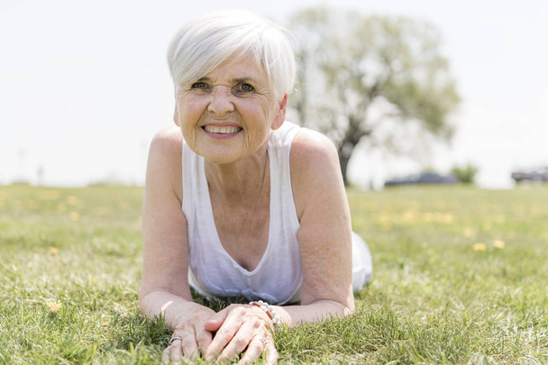 Active and happy senior woman outside in summer season - Photo, Image