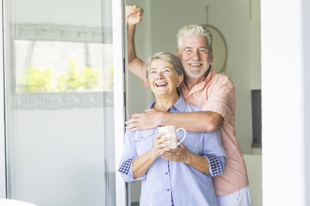 alegre casal adulto em casa olhando para fora, juntamente com alegria e paz
 - Foto, Imagem