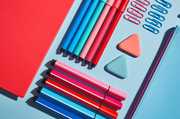 Pink notebook next to markers on a blue background - Фото, изображение