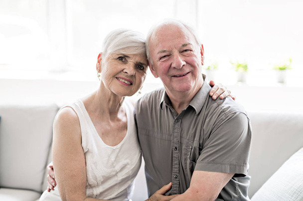 Affectionate attractive elderly couple sitting together on a couch - Foto, afbeelding