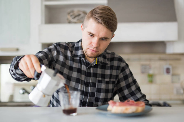 Essen, Morgen- und Menschenkonzept - schöner Mann trinkt Kaffee in der Küche - Foto, Bild