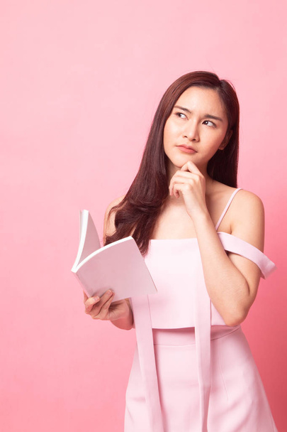 Young Asian woman with a book on pink background - Foto, imagen