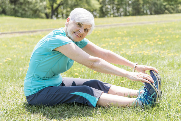 Senior Woman stretching In Park - Foto, afbeelding